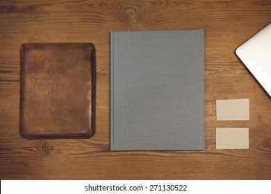 Blank leather case for tablet (for the application logo), book cover (booklet), and business cards on a wooden texture. Vintage style