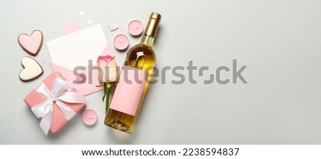 Blank letter, rose, bottle of wine, cookies, candles and gift on light background with space for text. Valentine's Day celebration