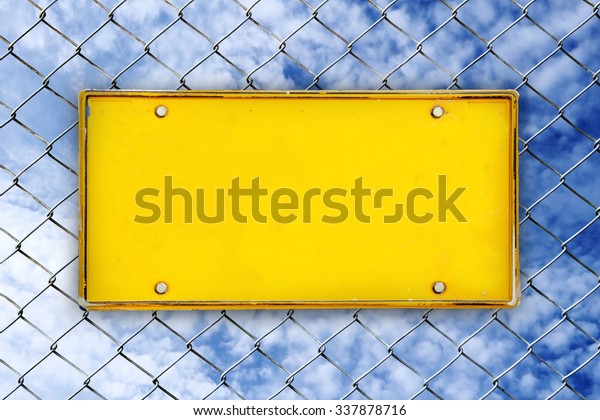 blank license plate on net fence and blur\
cloud spread on blue sky\
background