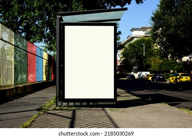 Blank Light Box And Glass Bus Shelter At Busstop. Green Street Setting. Urban Background. White Ad Poster And Commercial Space. Display Panel. Empty Vertical Outdoor Communication Space. Mockup Base