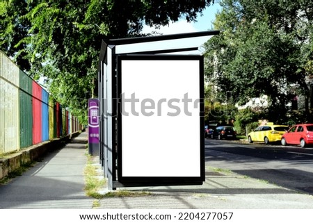blank light box and glass bus shelter at busstop. green street setting. urban background. white ad poster and commercial space. display panel. outdoor communication space. mockup base. ban and red car