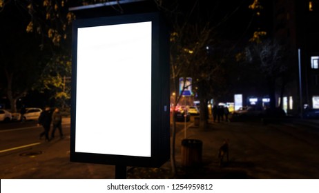 Blank Light Box Poster Copy Space Outdoors At Night With Unrecognizable Men Crossing The Road Ideal For Digital Signage, Information Board, Video Wall And Marketing Sale Discount Message