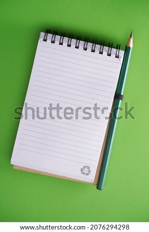 blank lined note pad and pencil on green background