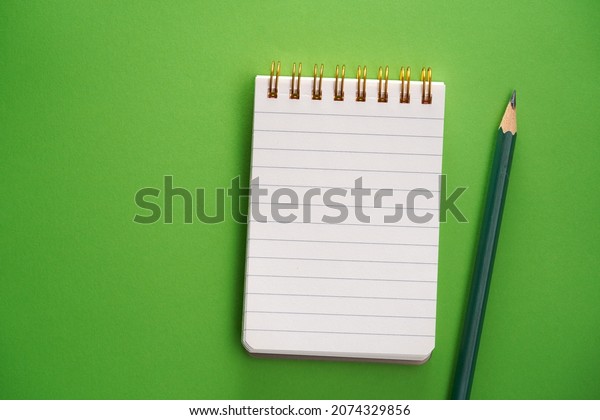 blank lined\
note pad and pencil on green\
background