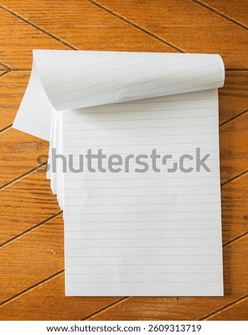 Blank lined notepad rests on a wood grain surface.  Perfect for adding text, notes, or designs.  Ideal for backtoschool, education, or office concepts. Clean and simple aesthetic.
