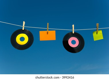 blank media on clothesline against blue sky, notecard and 45rpm records