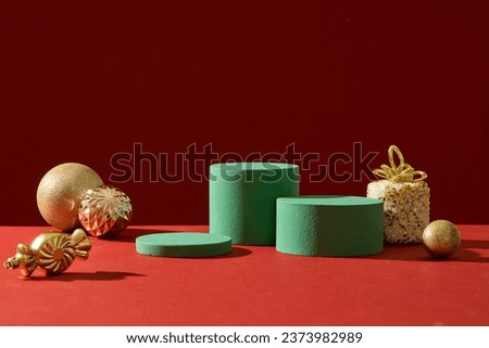 Blank minimalistic empty showcase template for advertising product with Christmas concept. Front view of green cylinder podiums displayed with cute yellow accessory on red background