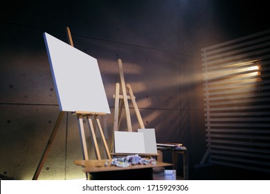 Blank Mock Up Canvas. Dark Art Studio Where There Are Wooden Easels, Palette And Abstract Picture Painted With Watercolor Paint