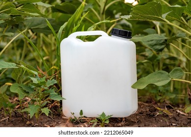 Blank Mockup White Plastic Jug For Herbicide Chemical In Cultivated Sunflower Field, Selective Focus