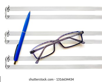 Blank music staff with with ten staves, treble and bass clefs and glasses and pen on it. Clean music sheet for musical notation and composing. Top view page with copy space - Powered by Shutterstock