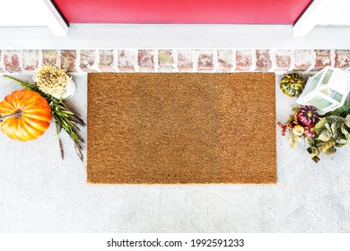 Blank natural door mat in front of entrance door with fall decor, thanksgiving mockup