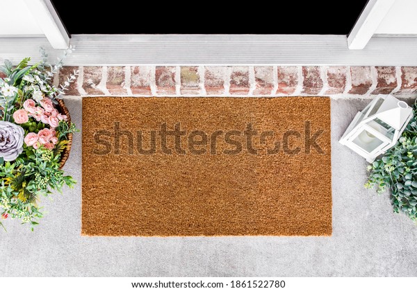 Blank natural door mat in front of entrance door\
with flowes, doormat\
mockup
