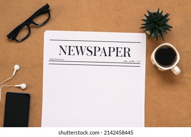 Blank newspaper, eyeglasses, coffee cup, mobile phone and small plant on wooden table . News mock up concept - Shutterstock ID 2142458445