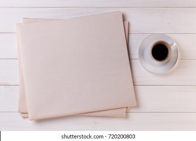 Blank Newspaper On White Wooden Table And A Cup Of Coffee. Top View Of Daily News Mock Up. Space For Your Text Or Image.