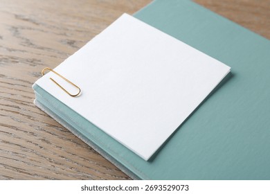 Blank note with clip and notebook on wooden table, closeup. Space for text