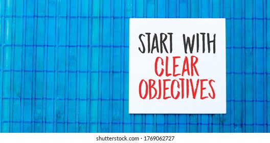 Blank Note Pad With Start With Clear Objectives Text On Blue Wooden Background