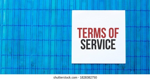 blank note pad with text TERMS OF SERVICE on blue wooden background