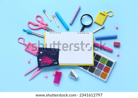 Blank notebook with credit cards and different stationery on blue background