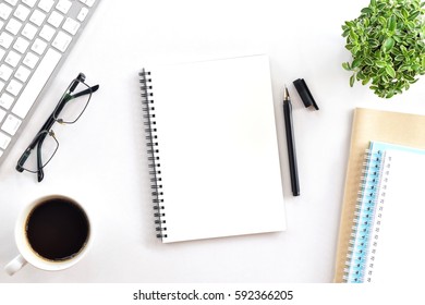 Blank notebook page is on top of white office desk table. Top view, flat lay. - Shutterstock ID 592366205