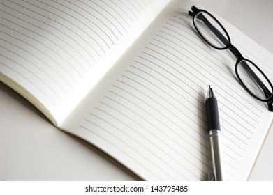 blank notebook pages with pen and glasses - Shutterstock ID 143795485