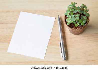 Blank notebook paper with little plants in eco pot on a wooden table. picture used for add text or education message. green fresh. white note with pencil. 