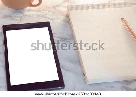 Blank notebook, pen and digital reader on marble table. Digital device and notebook for reading and notes. Digital and manual writing