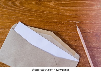 Blank notepad and brown envelope on wooden board background