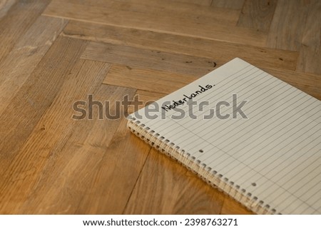 Blank notepad in class on wooden desk for student learning Dutch written language. Nederlands subject for adult learning with handwritten notes and writing exercises for personal development