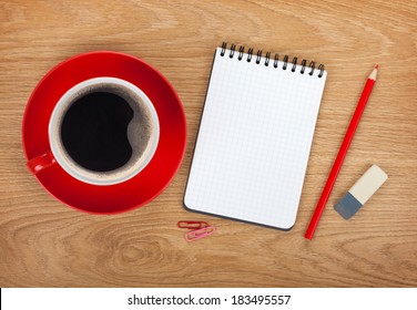 Blank notepad with office supplies and red coffee cup on wooden table. Above view - Powered by Shutterstock