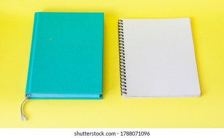 Blank notepad on yellow table, next to turquoise notepad. Business concept