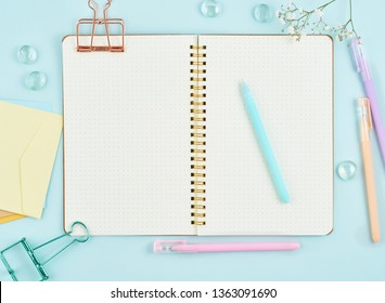 Blank Notepad Page In Bullet Journal On Blue Office Desktop. Top View Of Modern Bright Table With Notebook And Flower. Mock Up, Copy Space.