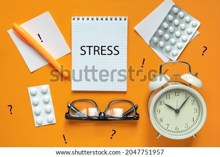 Blank of Notepad with the Word Stress, Pen, Clock and Antidepressants on orange Background. Top view, Flat lay. Copy space. Stop Depression. Education, Exam, Work Stress or Tension concept.