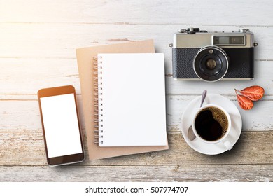 Blank notepad,old camera and coffee cup on white wooden table with copy space