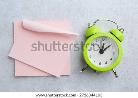 Blank notes and alarm clock on gray textured table, flat lay