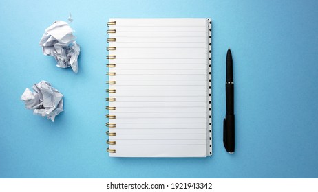 Blank Open Notebook, Pen And Crumpled Paper Wads On Blue Background. Copy Space. Top View Of Blank Open Notebook, Concept Of Education Or Business