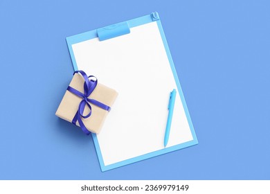 Blank open notebook with pen and gift box on blue background. New year goals
