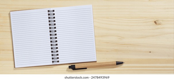 Blank open notebook and pen made from recycled material. Wooden banner, top view with space for text - Powered by Shutterstock