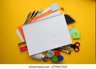 Blank Open Notebook Surrounded by Colorful School Supplies on Yellow Background Top View