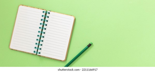 Blank Open Spiral Notepad. Paper Notebook And Pencil With Eraser On Light Green Background. Space For Text, Overhead View