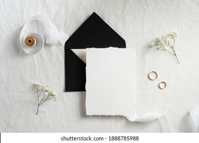 Blank paper card and black envelope on bed. Wedding invitation card mockup. Top view with copy space. 