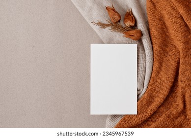 Blank paper card mock up, fall leaves on a neutral beige and bright ginger, orange knitted textile background, aesthetic autumn wedding invitation, business brand design template, flat lay Foto Stock