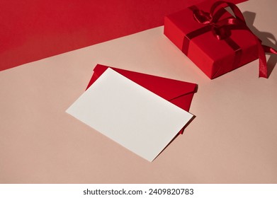 Blank paper card mockup, red envelope and gift box on peach beige background with harsh light shadows. Minimal Valentine day, birthday celebration concept, greeting postcard, love letter template.