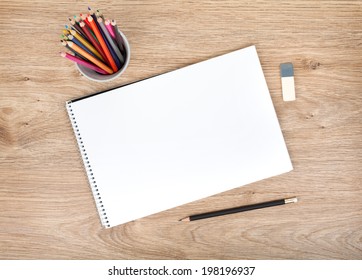 Blank paper and colorful pencils on the wooden table. View from above - Powered by Shutterstock