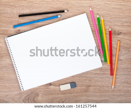 Blank paper and colorful pencils on the wooden table. View from above