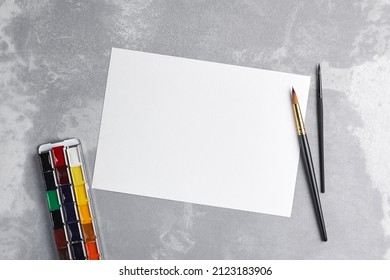 Blank Paper Mockup For Watercolor Drawing, Artwork Or Illustration. White Paper Sheet With Paintbrush And Watercolor Paints Palette