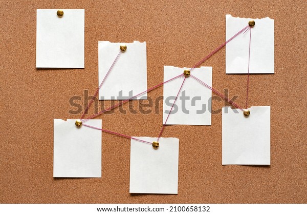 Blank paper notes are pinned\
to a cork board. The concept of detective investigation. Copy\
space.