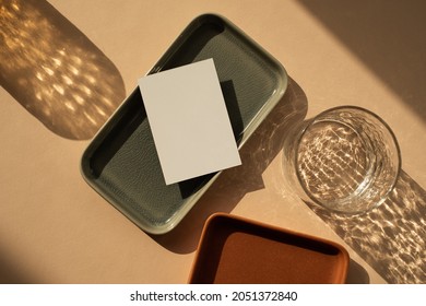 Blank Paper Sheet Card With Mockup Copy Space. Minimal Luxury Aesthetic Business Brand Template. Glass With Sunlight Shadows, Ceramic Plates On Neutral Peachy Background. Flat Lay, Top View