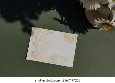 Blank Paper Sheet Card Watercolor Mockup,bouquet Of Daisies Flowers And Sunlight Shadow Top View On Green Background.Copy Space. Template, Invitation, Greeting Card, Wedding Stationary Scene