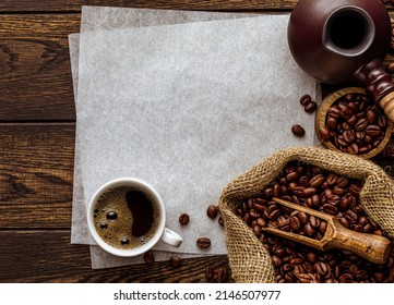 Blank paper sheet copy space over rustic coffee background with wood texture. Freshly brewed aromatic drink in cup, vintage cezve pot, sack, spoon and bowl with roasted coffee grains