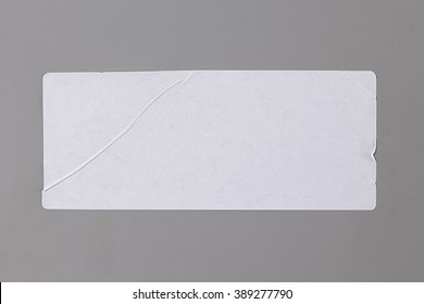 Blank Paper Tag. Label isolated on Grey Background. Sticker or Paper Adhesive with Wrinkles and Scratches. Close Up. Top View with Copy Space for Text or Image